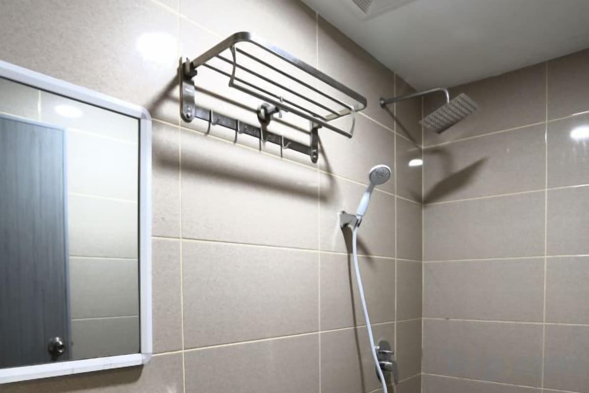 Une salle de bain avec une douche, un porte-serviettes et un miroir.