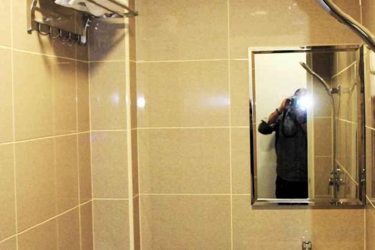 A bathroom with a mirror, a shower, and a towel rack.