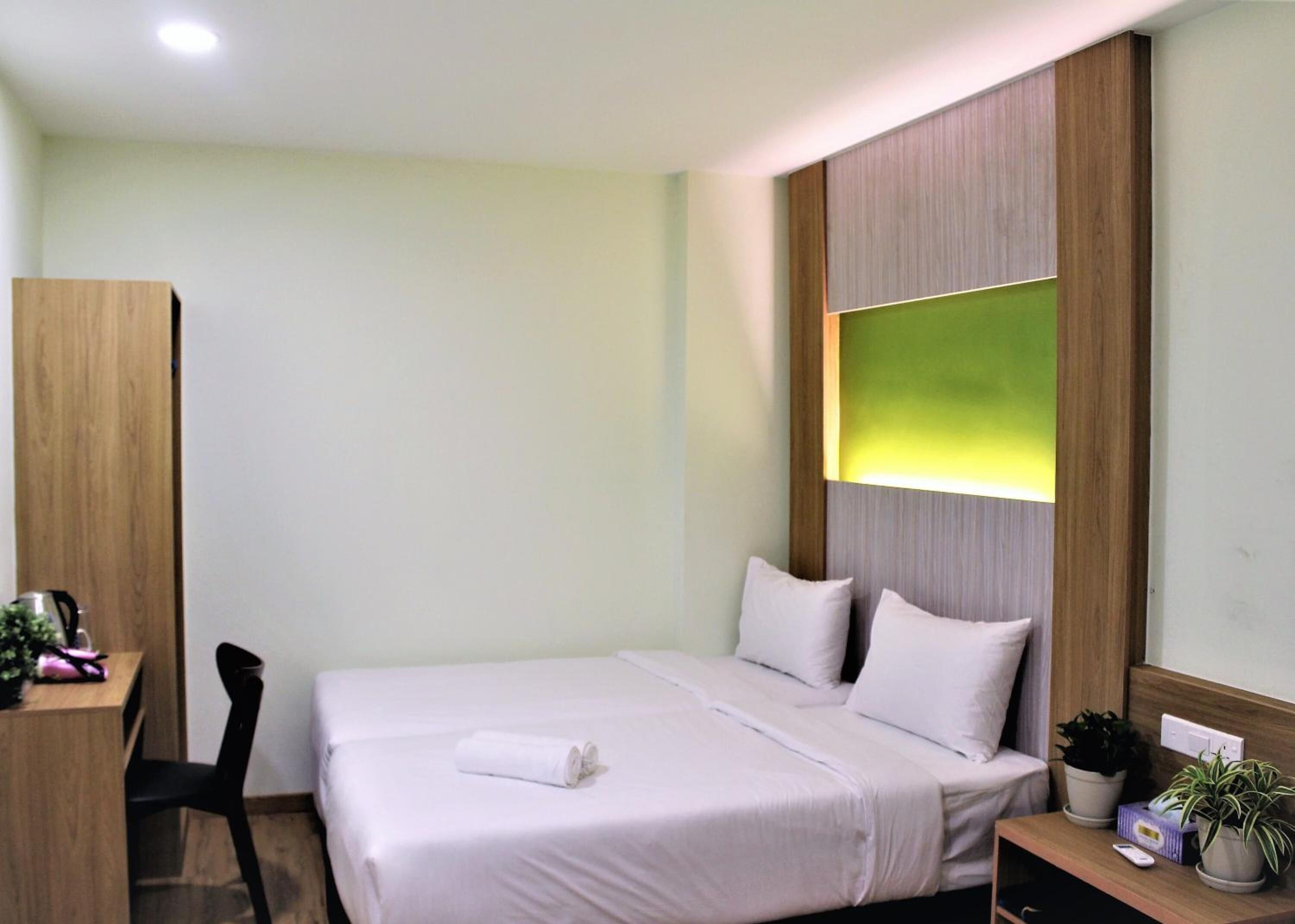 A neatly arranged hotel room with a bed, a desk, and a chair.