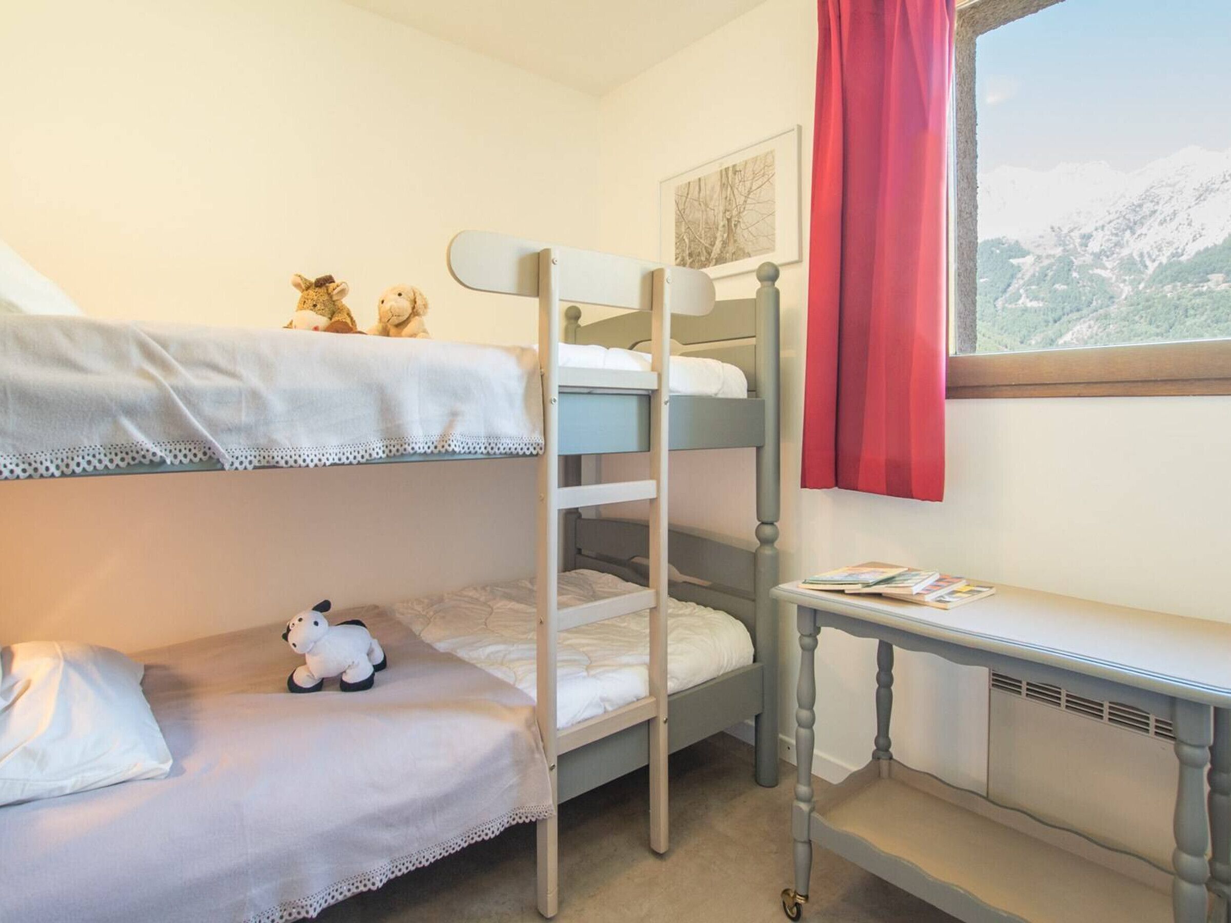 A bunk bed room with a small desk and a window with a mountain view.