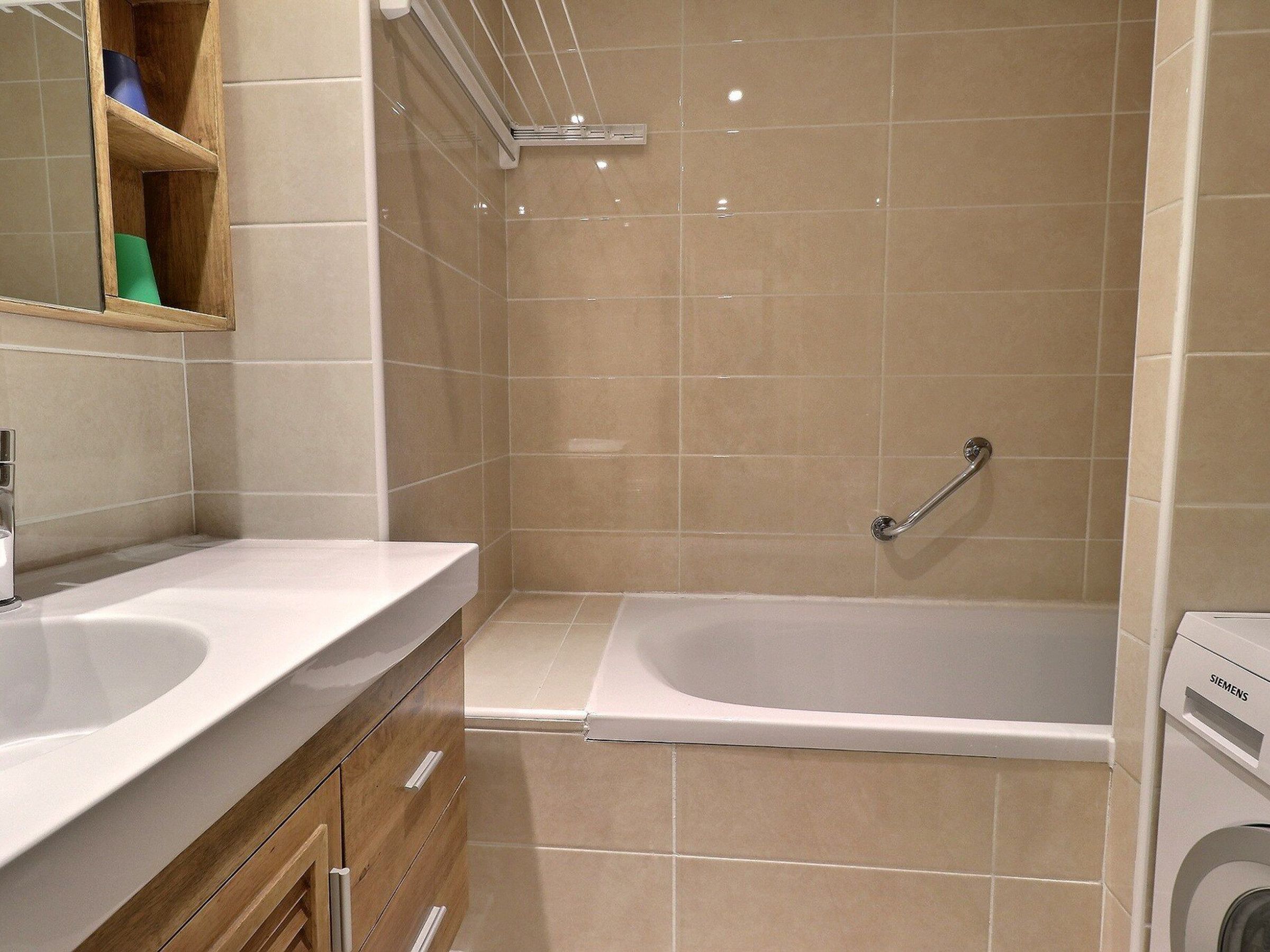 Une salle de bain avec deux lavabos, une douche et un lave-linge encastré.