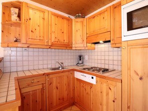 A kitchen with wooden cabinets, a sink, a stove, and a microwave.
