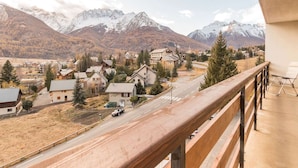 A balcony with a view of a mountain town, including houses, a road, and a church. - 3-Room Apartment 6 Pers, Balconies, Pets Allowed, Near Shops (Le Monêtier-les-Bains)