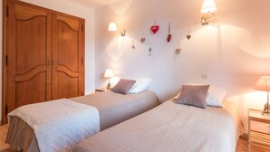 A bedroom with two beds, wooden wardrobe, wall-mounted lights, and heart-shaped decorations. - 3-Room Apartment 6 Pers, Balconies, Pets Allowed, Near Shops (Le Monêtier-les-Bains)