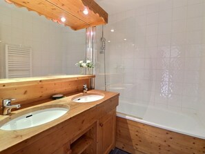 Een badkamer met twee wastafels, een spiegel en een douche.