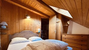 Ein Zimmer mit Holzboden, einem Bett, einem Schminktisch und einem Dachfenster.