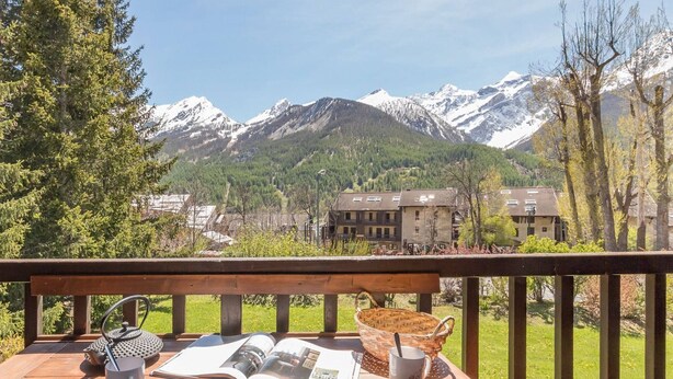 Eine Holzterrasse mit Picknicktisch, einem Buch, einer Tasse und einem Korb.