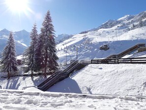 Een berglandschap bedekt met sneeuw, met een kabelbaan en houten trappen.