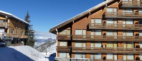 A multi-story wooden hotel with balconies, set against a snowy mountain backdrop.