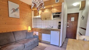 Une cuisine de taille réduite, dotée de meubles en bois, d’un four à micro-ondes et d’un petit réfrigérateur.