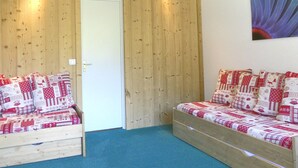 Een kamer met een houten wand, een deur en twee houten banken met gestreepte kussens.