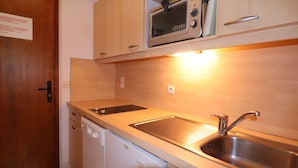 Een praktische keuken met een ingebouwde magnetron, een vaatwasser en een roestvrijstalen spoelbak.