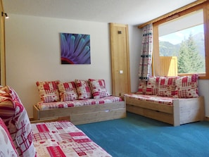 A cozy room with two wooden benches, a large window with a view of trees, and a wall-mounted painting. - Charming bright studio, ski-in/ski-out (Méribel)