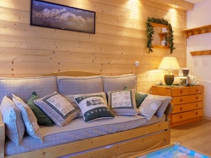 A cozy room with a wooden wall, a framed picture, a lamp, and a dresser.