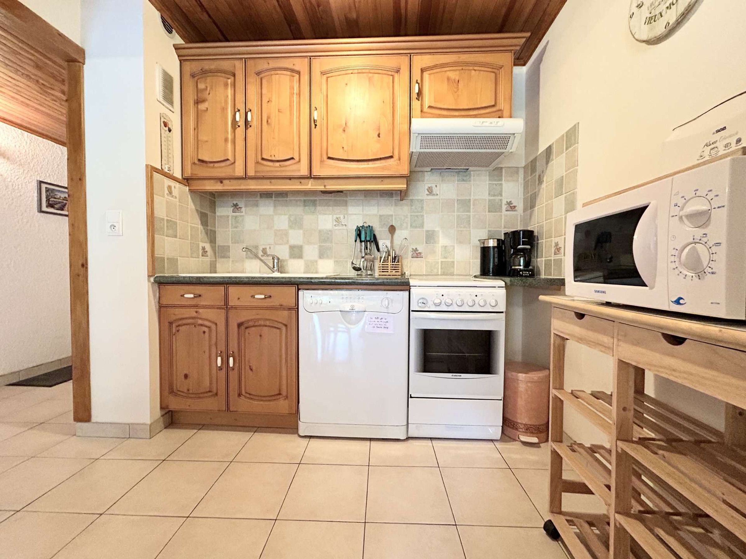 A kitchen with wooden cabinets, a dishwasher, an oven, a microwave, and a coffee maker.
