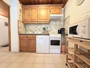 Una cocina con armarios de madera, lavavajillas, horno, microondas y cafetera.