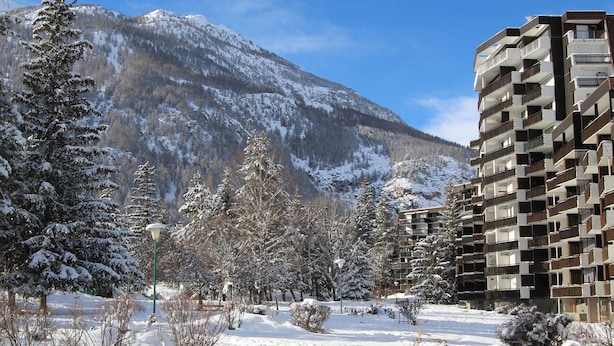 Una montaña nevada con un moderno edificio de apartamentos en primer plano.