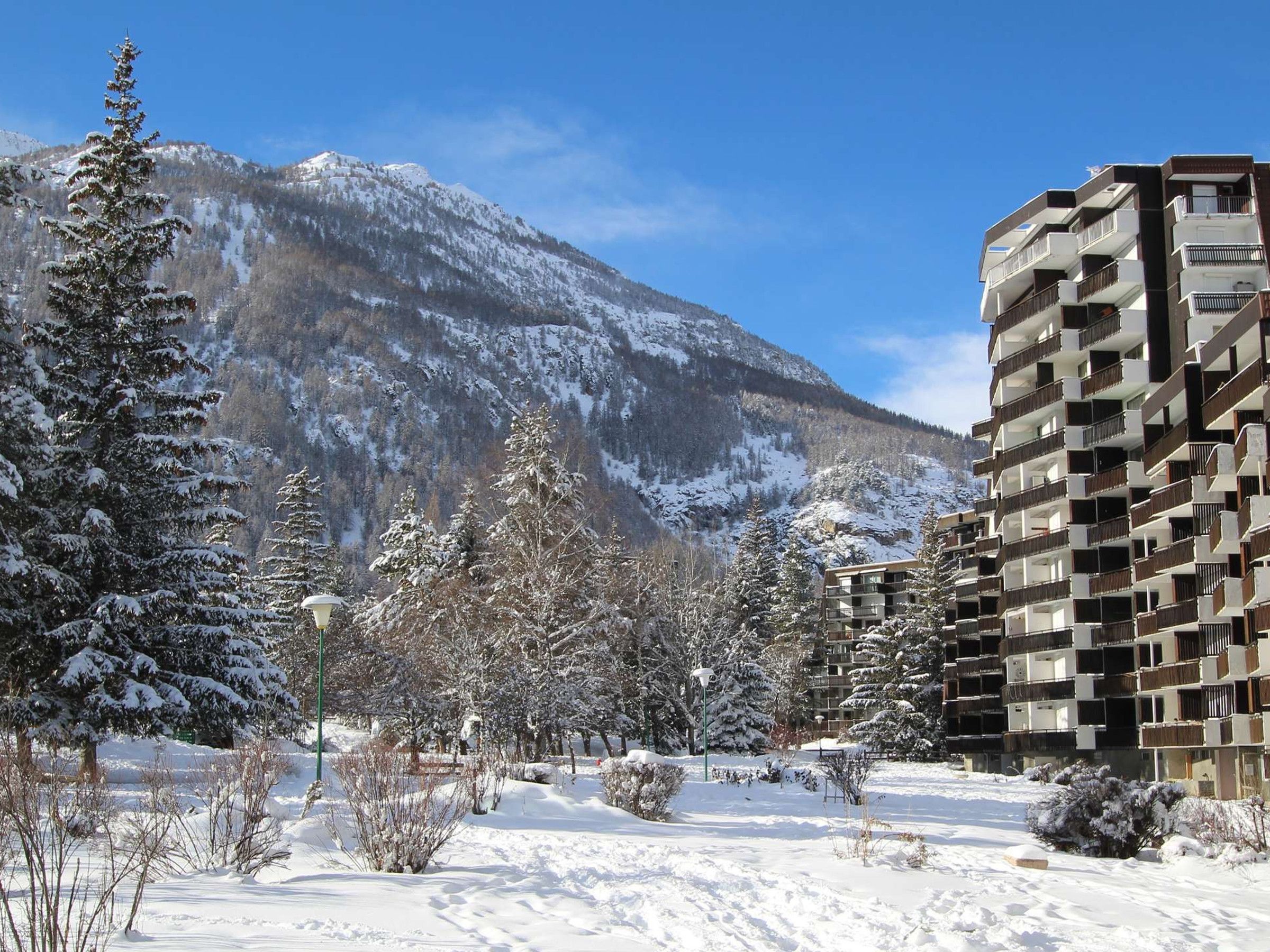 Paisaje montañoso nevado con un edificio de varios pisos y balcones.