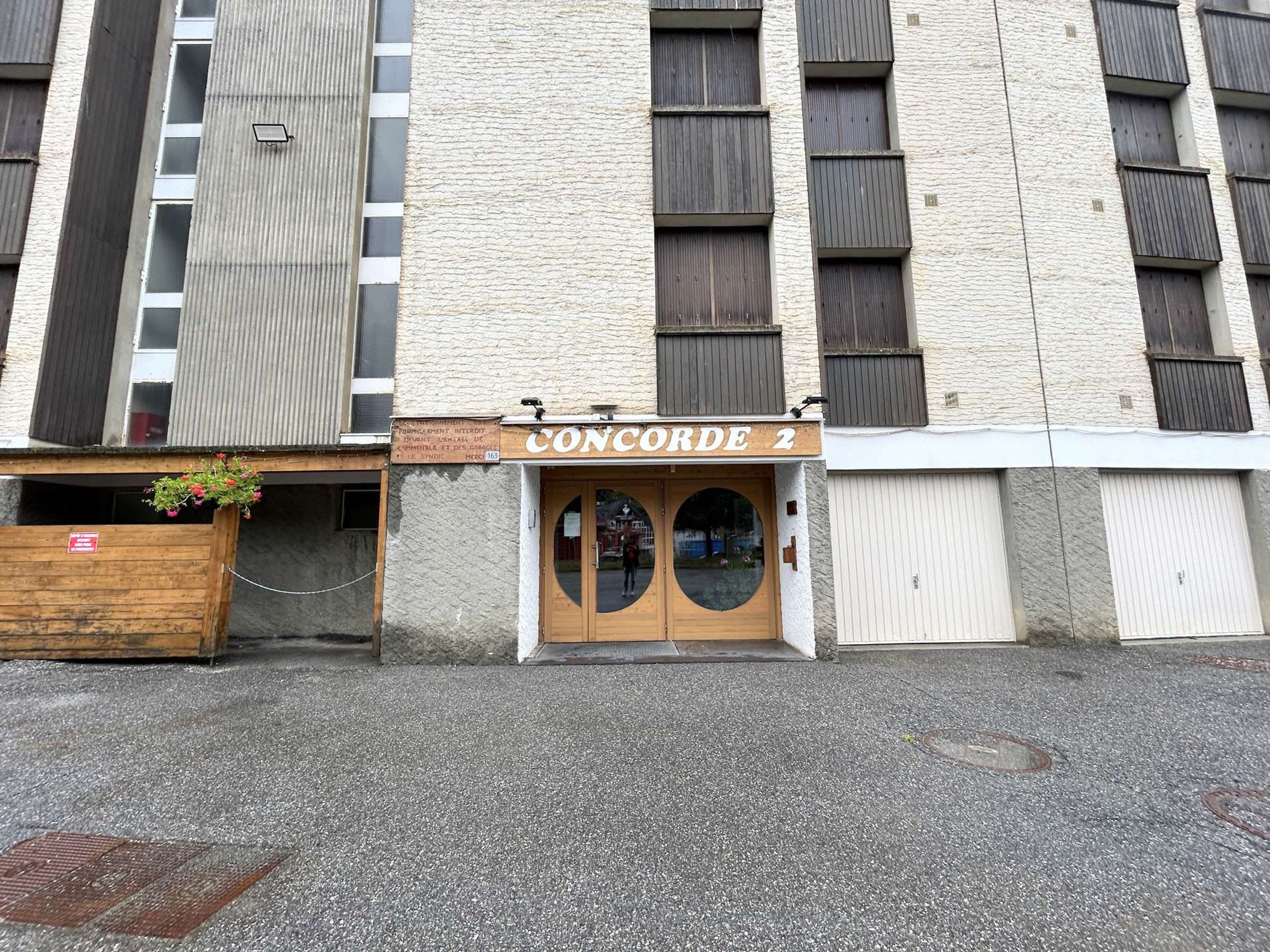 A building with a sign reading 'CONCORDE 2' above a wooden door with two circular windows.