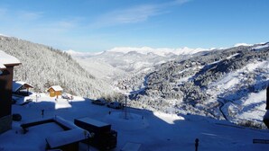 Schneebedeckte Berglandschaft mit einer kleinen Berghütte und einer Skipiste.