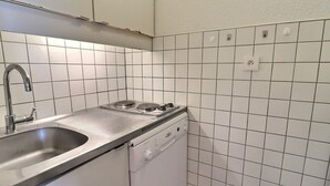 Eine kompakte Küche mit einer Edelstahlspüle, einem Einbauherd und einem Geschirrspüler.
