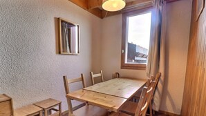 Ein Essbereich mit einem Holztisch und Stühlen, einem kleinen Fenster mit Vorhängen und einem Spiegel an der Wand.