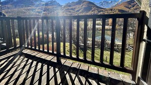 A wooden deck with a metal railing overlooking a mountainous landscape with a lake.