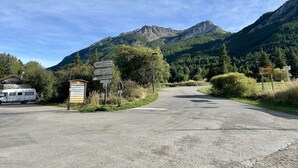 A road leading to a mountain with a sign indicating 'Le Gros Moutier'.