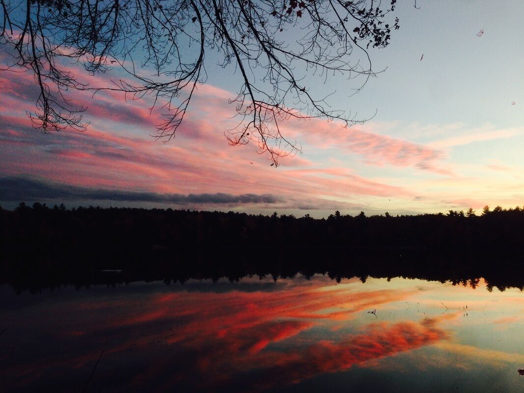 A serene lake at sunset with a clear reflection of the sky.