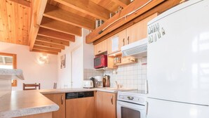 A compact kitchen with wooden cabinets, a white refrigerator, a microwave, a toaster, and a dishwasher.