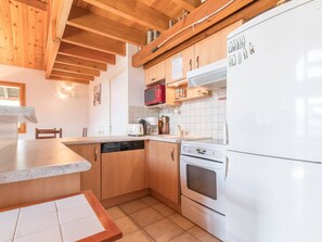 A compact kitchen with wooden cabinets, a white refrigerator, a microwave, a toaster, and a dishwasher.