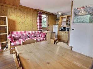 Een gezellig houten interieur met een geruit bankje, een eettafel en een keukenhoek.