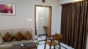 Un salón con un sofá, una silla de madera, una mesa de centro y un cuadro en la pared.