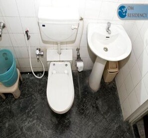 Un baño con inodoro, lavamanos y un cubo azul.