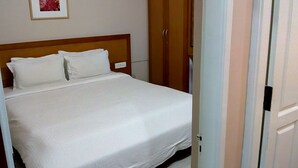 Una cama bien hecha con ropa de cama blanca en una habitación con cabecera de madera.