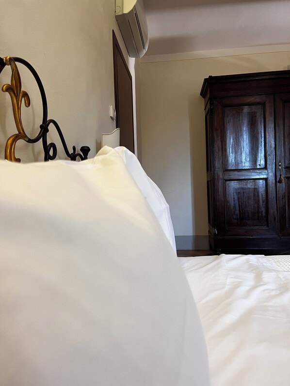 A hotel room with a bed, a wooden wardrobe, and a wall-mounted air conditioning unit.