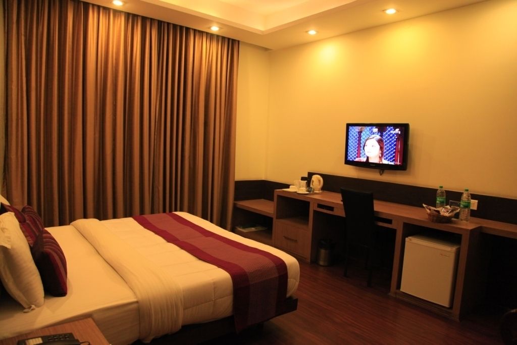 Ein Hotelzimmer mit Bett, Schreibtisch, Fernseher und Minibar.