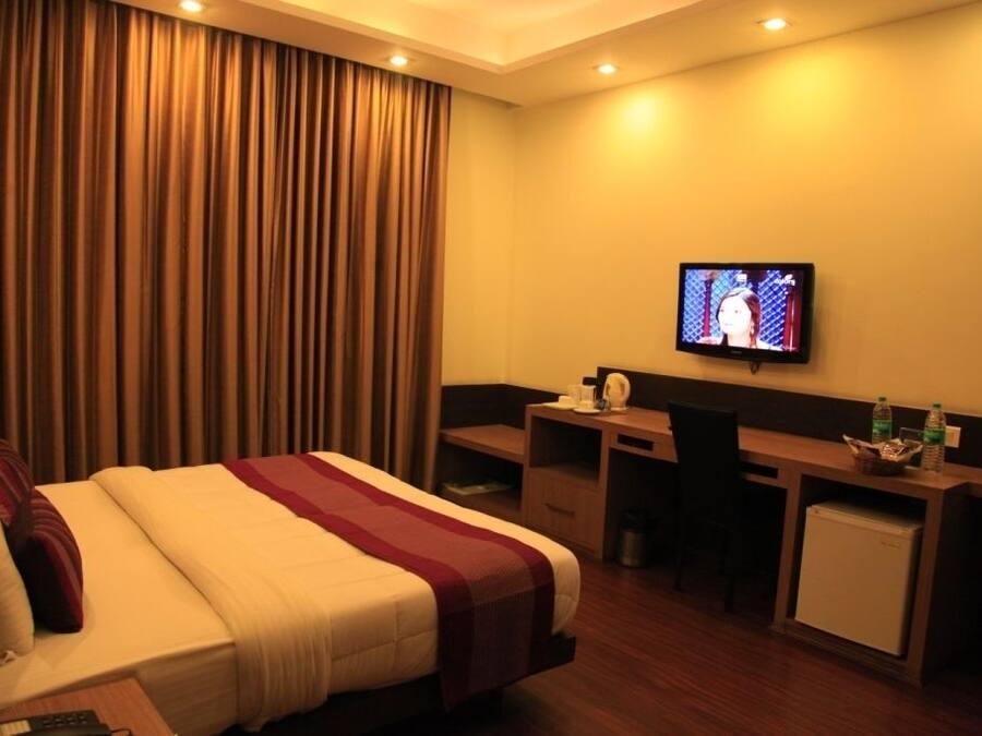 Ein Hotelzimmer mit Bett, Schreibtisch, Fernseher und Minibar.
