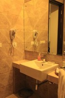A bathroom with a sink, two hair dryers mounted on the wall, and a mirror.