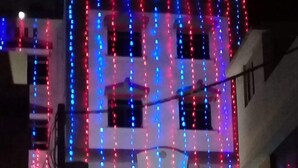 Un hôtel avec une enseigne indiquant « HÔTEL GOMTI » et une décoration lumineuse en forme de spirale au-dessus de l’entrée.
