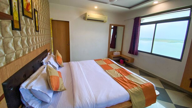 Une chambre d’hôtel équipée d’un lit, d’un ventilateur de plafond, d’un appareil de climatisation, d’une fenêtre avec vue et d’un miroir.