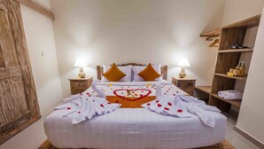 A neatly made bed with white linens, two pillows, and a heart-shaped arrangement of rose petals on the bedspread. - Vimala Ubud Hotel (Ubud)
