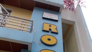 Un cartel de hotel con el nombre 'ROSE HOTEL' en letras grandes y negritas.