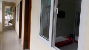 Un pasillo con puertas que dan a una habitación con cama y televisor.
