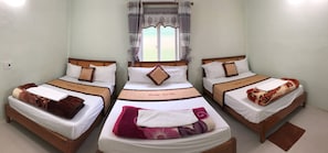 A hotel room with three single beds, each with a wooden headboard and white bedding. A window with patterned curtains is visible, and the room has light-colored walls. - Rose Hotel (Phong Nha)