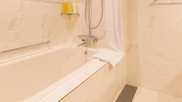 Et moderne badeværelse med badekar, bruser og et hylder med toiletartikler.