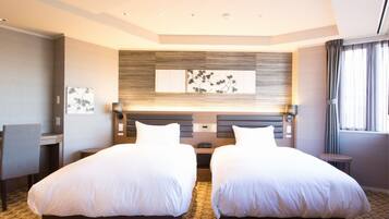 A hotel room with two beds, a headboard with a wood panel design, a small desk, and a chair.