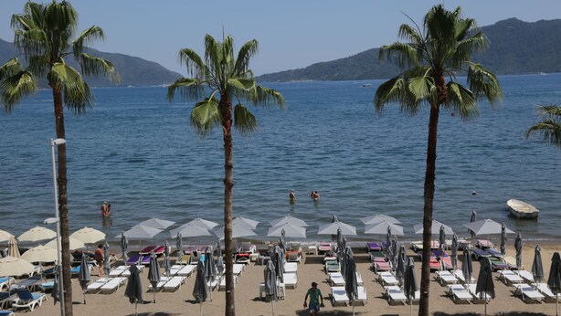 A beach with rows of sun loungers and umbrellas, palm trees, and a calm sea. - Geo Beach Hotel Marmaris (Marmaris)