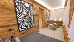 A spa room with wooden walls, a massage table, two massage chairs, and a large leaf-patterned artwork. - Hotel-Gasthof Thüringer Hof (Floh)