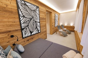 Un cuarto de spa con paredes de madera, una camilla de masaje, dos sillas de masajista y una gran obra de arte con motivos de hojas.